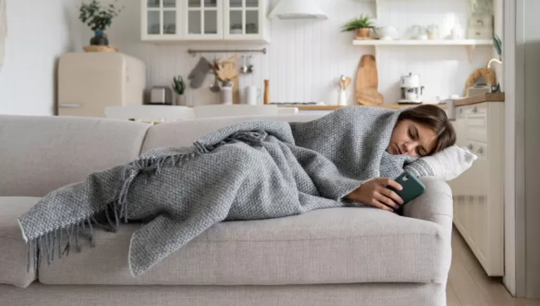 someone lying down on the sofa checking their phone