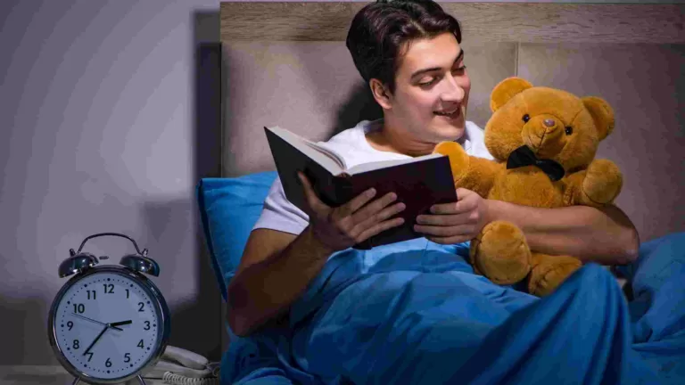 person reading a book in bed with a teddy bear