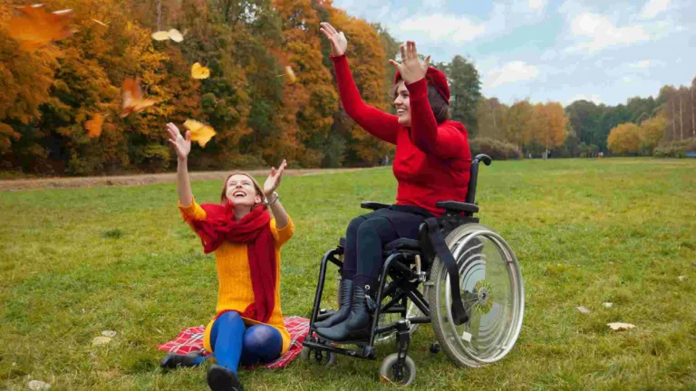 people having fun outside on a grassy plain and playing with autumn leaves