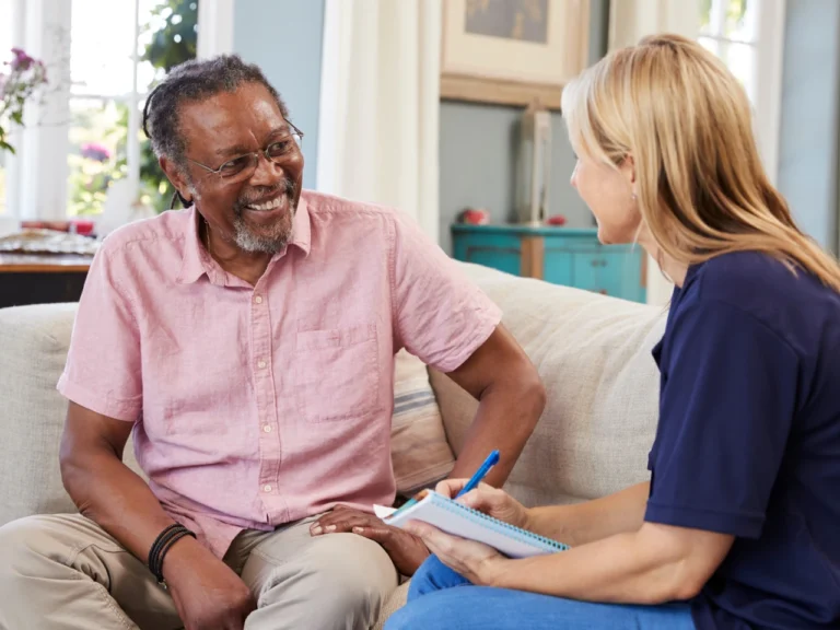 an older man sitting and having a conversation with a female support worker