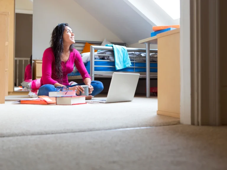a woman seated in the middle of her room, smiling